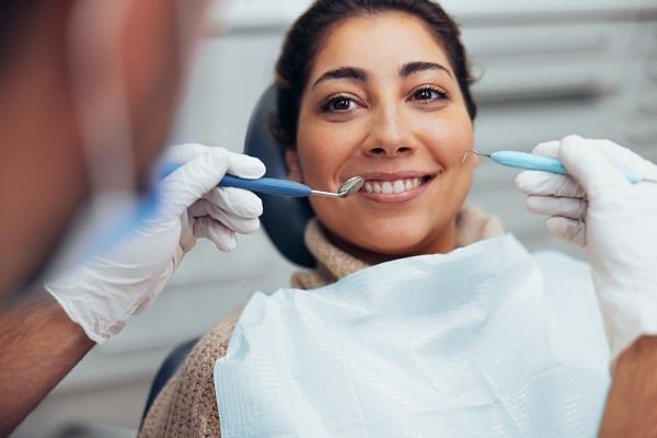 Smiling woman receiving a dental checkup and cleaning at a professional clinic.