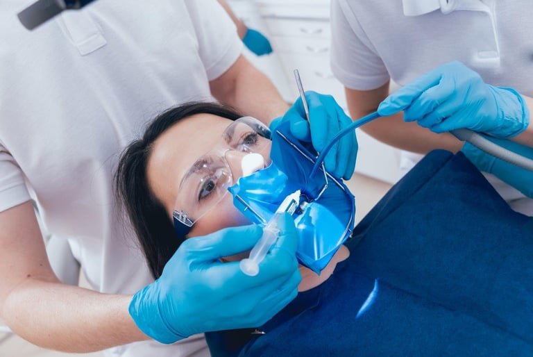 A female patient undergoes a professional root canal procedure with a blue dental dam and syringe.